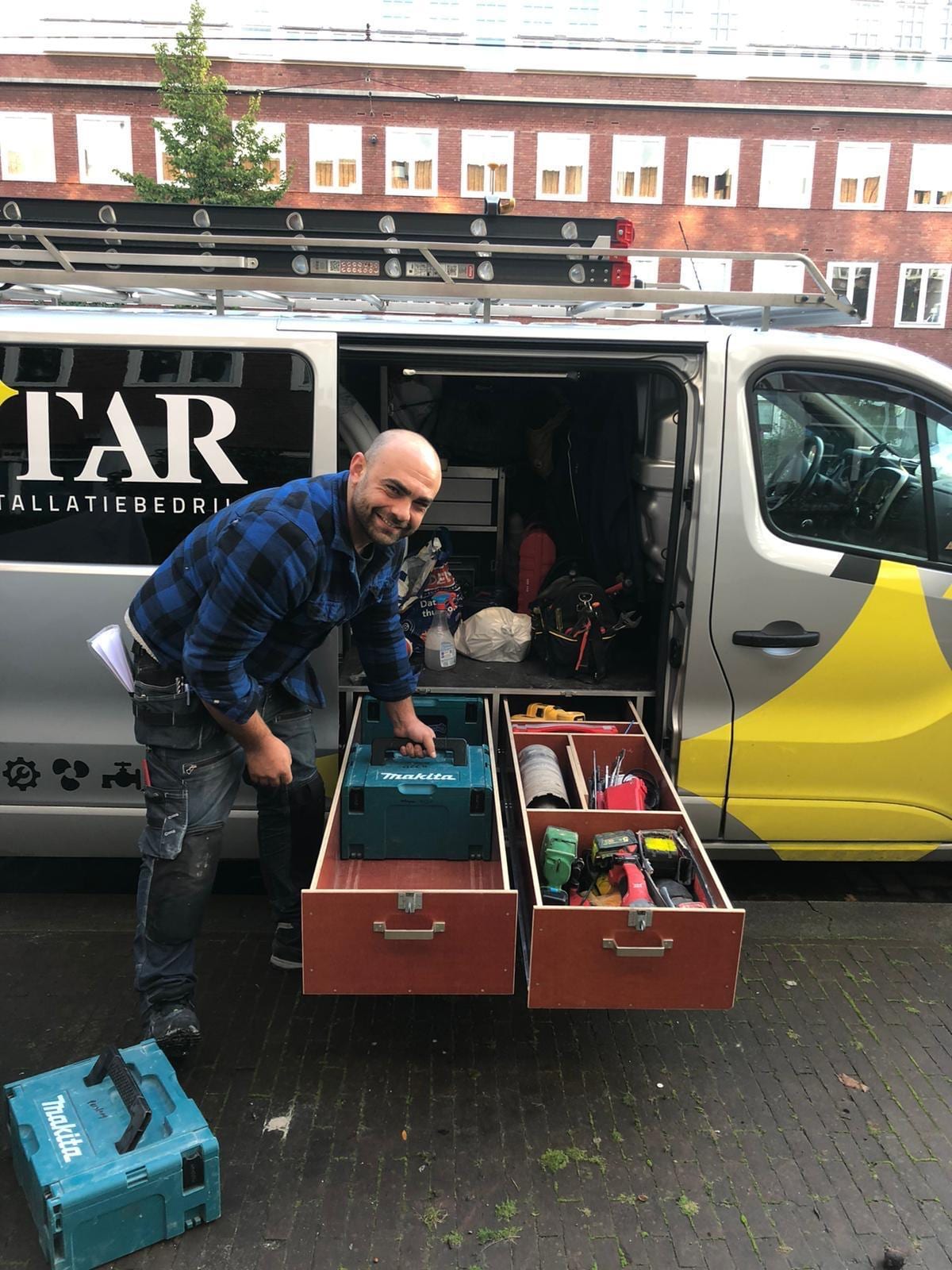 Vakman van Star Installatie bij de bedrijfsbus met al het gereedschap binnen handbereik