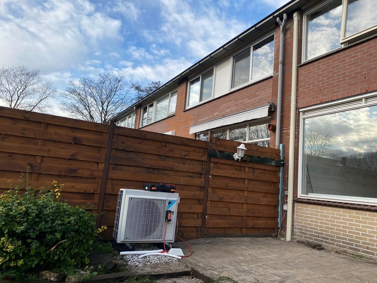 Buitenunits van een warmtepomp naast een woning
